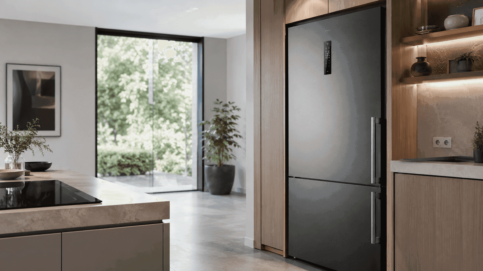 Moderner, leiser schwarzer Kühlschrank in einer hellen, minimalistischen Küche mit großen Fenstern und Pflanzen.